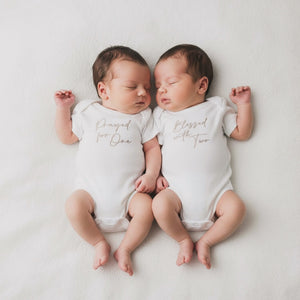 Newborn twins wearing ivory twin vest set with "Prayed for One" and "Blessed with Two" embroidery