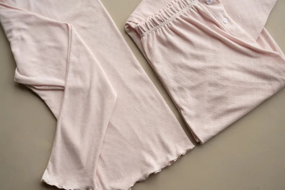 Soft pastel pink Heart Pointelle Pjs with heart knit pattern, elasticated waistband, buttoned trousers, and lettuce-edge hems.