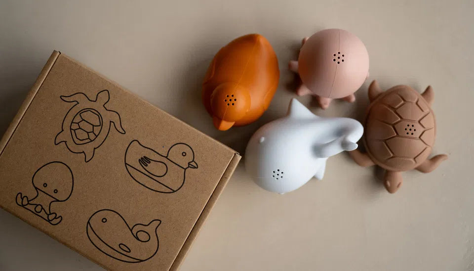 The Splash Friends bath toy set with turtle, duck, whale, and octopus in soft silicone next to gift box