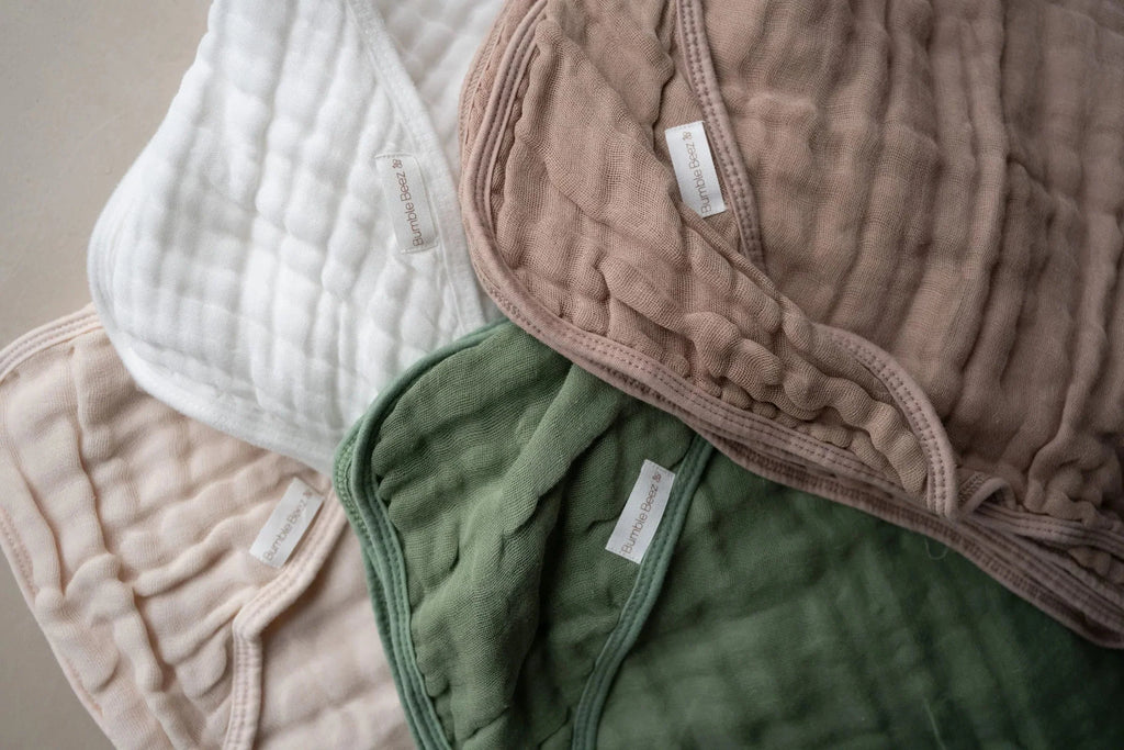 Soft hooded muslin towels for babies in white, sage green, latte, and beige colors, pack of two.