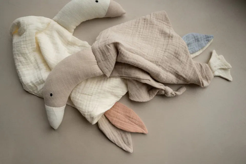 The Goose Comforter plush cotton muslin baby soothing toy in oat pastel blue and milk rosa pink colors