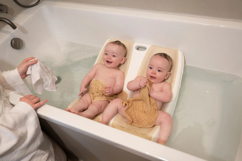 Twin Bath with two happy babies bathing side by side in a bathtub, designed for twins aged 0-6 months.