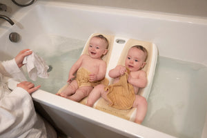 Twin Bath with two happy babies bathing side by side in a bathtub, designed for twins aged 0-6 months.